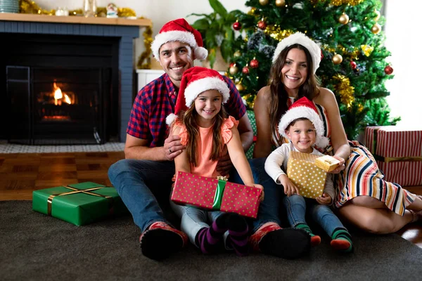 Glad Kaukasiska Familj Bär Tomte Hatt Håller Presenter Tittar Kameran — Stockfoto