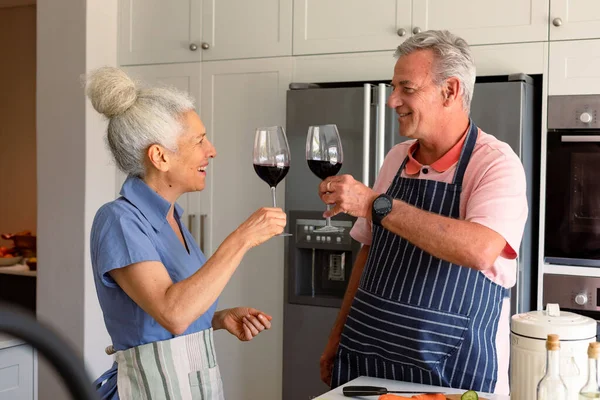 キッチンに立つ幸せな白人のシニアカップル ワインを飲み 一緒に食事を準備します 家庭での健康的な退職生活 — ストック写真