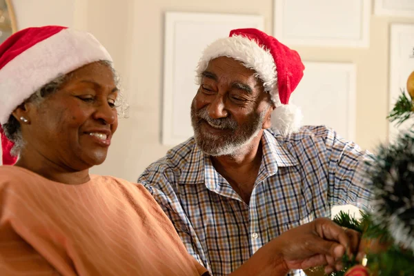 クリスマスツリーを飾る幸せなアフリカ系アメリカ人のシニアカップル クリスマスの時間と祭りを一緒に家で — ストック写真