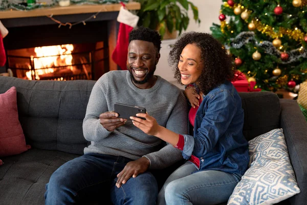 幸せなアフリカ系アメリカ人のカップルは スマートフォンでのビデオ通話 背景にクリスマスの装飾を持っている クリスマスやお祭りや通信技術は — ストック写真