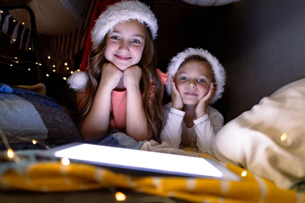 幸せな白人の兄弟はサンタの帽子をかぶっており クリスマス時にタブレットを使用しています 家庭での子供時代やクリスマスやお祭りや伝統 — ストック写真