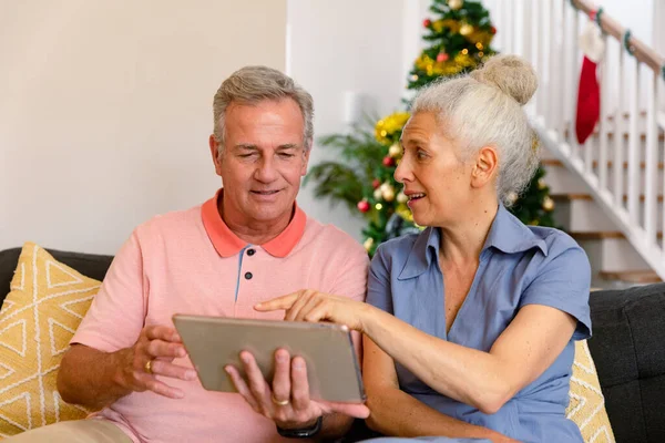 快乐的高加索老年夫妇坐在沙发上 在圣诞节的时候用平板电脑 健康的退休生活方式 — 图库照片