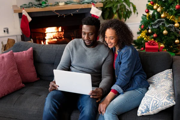 ラップトップでビデオ通話をしている幸せなアフリカ系アメリカ人のカップル 背景にクリスマスの装飾 クリスマスやお祭りや通信技術は — ストック写真