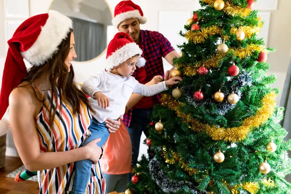 クリスマスツリーを飾る サンタの帽子をかぶって幸せな白人の両親と息子 クリスマスの時間と祭りを一緒に家で — ストック写真