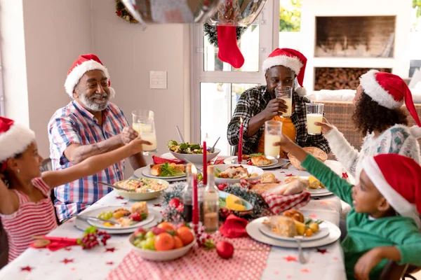 Ευτυχισμένη Οικογένεια Πολλών Γενεών Που Φοράει Καπέλα Σάντα Τρώει Χριστουγεννιάτικο — Φωτογραφία Αρχείου