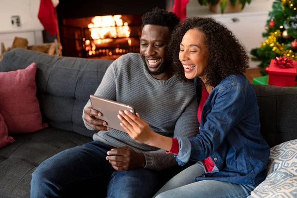 幸せなアフリカ系アメリカ人のカップルタブレット バックグラウンドでクリスマスの装飾にビデオ通話を持っている クリスマスやお祭りや通信技術は — ストック写真