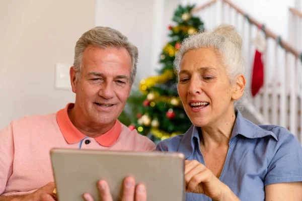 快乐的高加索老年夫妇坐在沙发上 在圣诞节的时候用平板电脑 健康的退休生活方式 — 图库照片