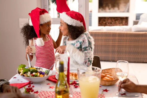 Feliz Madre Afroamericana Hija Con Sombreros Santa Claus Hablando Mesa —  Fotos de Stock