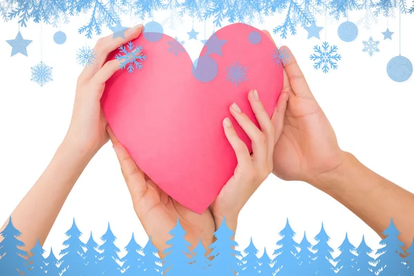 Composite image of couple holding a paper heart — Stock Photo, Image