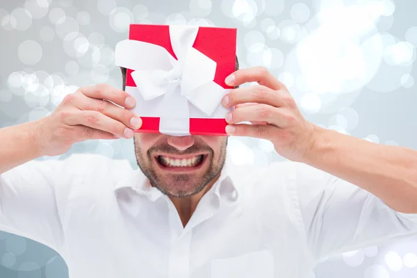 Imagen compuesta del hombre festivo sosteniendo el regalo de Navidad — Foto de Stock