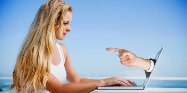 Bionda usando il suo computer portatile in spiaggia — Foto Stock