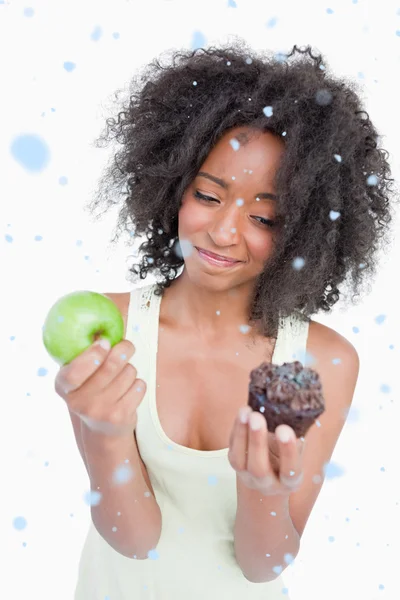 Junge Frau zögert kaum zwischen einem Muffin — Stockfoto