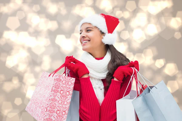 Imagen compuesta de morena festiva sosteniendo bolsas de compras — Foto de Stock