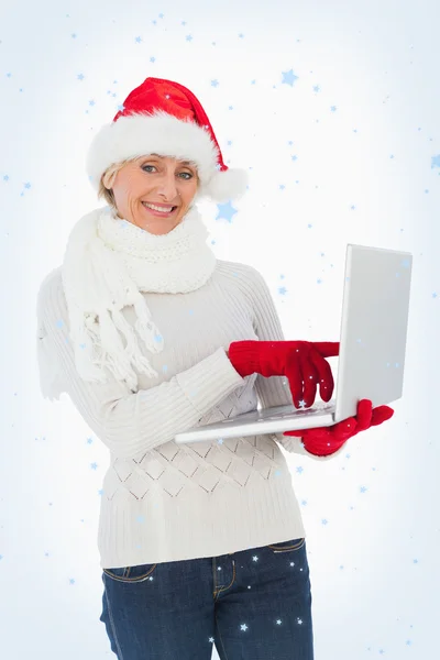 Σύνθετη εικόνα εορταστική γυναίκας χρησιμοποιώντας φορητό υπολογιστή που είναι χαμογελώντας σε κάμερα — Φωτογραφία Αρχείου