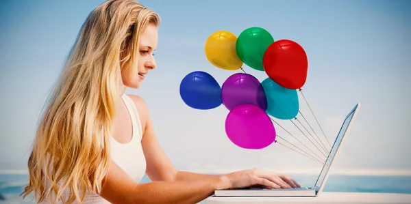 Blonde met behulp van haar laptop op het strand — Stockfoto