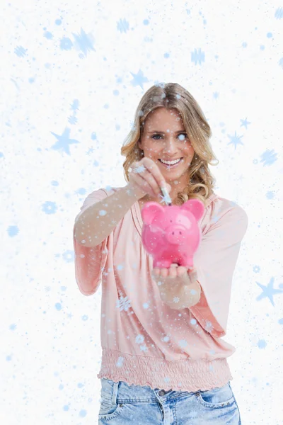 Smiling woman putting money into a piggy bank — Stock Photo, Image