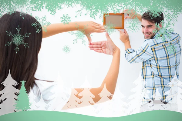 Happy young couple putting up picture frame — Stock Photo, Image