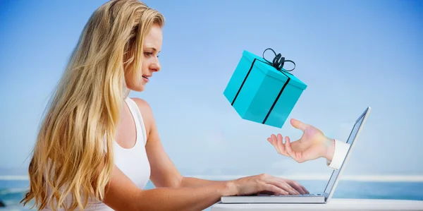 Blonde met behulp van haar laptop op het strand — Stockfoto