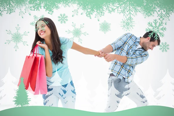 Attractive young man pulling his shopaholic girlfriend — Stock Photo, Image