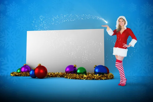 Composite image of pretty girl presenting in santa outfit — Stock Photo, Image