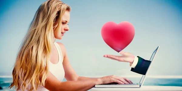 Blonde met behulp van haar laptop op het strand — Stockfoto