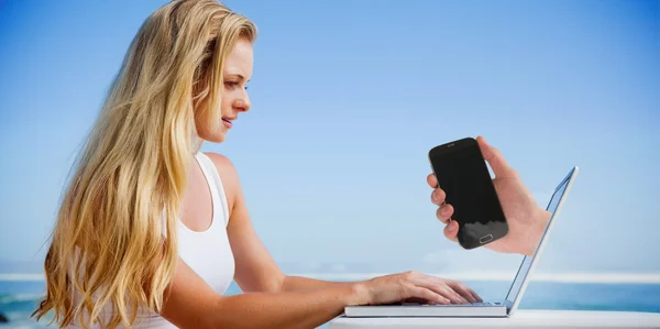 Blondine benutzt ihren Laptop am Strand — Stockfoto