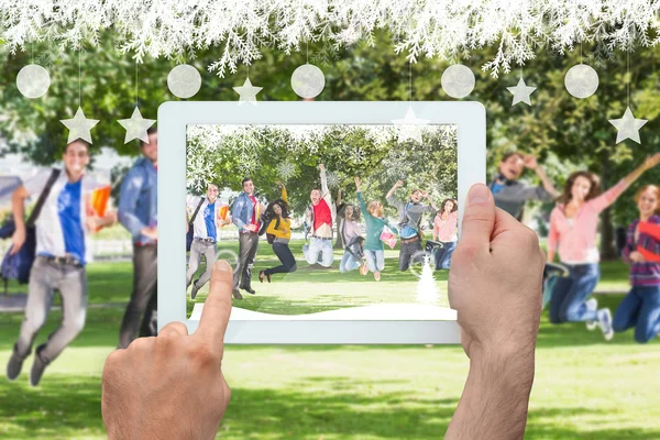 Hand met Tablet PC pagainst studenten springen — Stockfoto