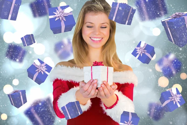 Composite image of pretty girl in santa outfit holding gift — Stock Photo, Image