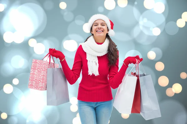 Imagen compuesta de morena festiva sosteniendo bolsas de compras — Foto de Stock