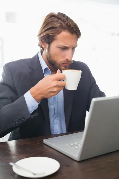 Empresário trabalhando em seu laptop tomando café — Fotografia de Stock