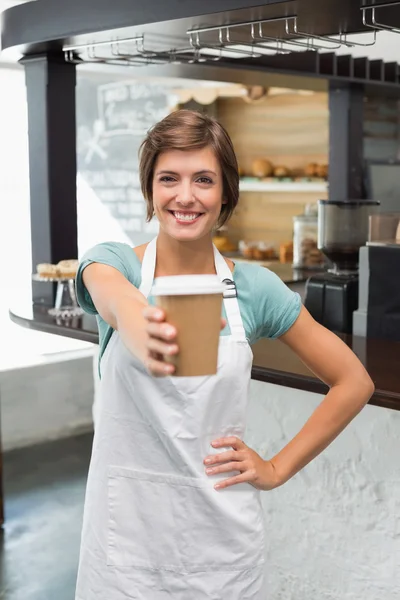 Bonito barista sorrindo para câmera segurando copo descartável — Fotografia de Stock