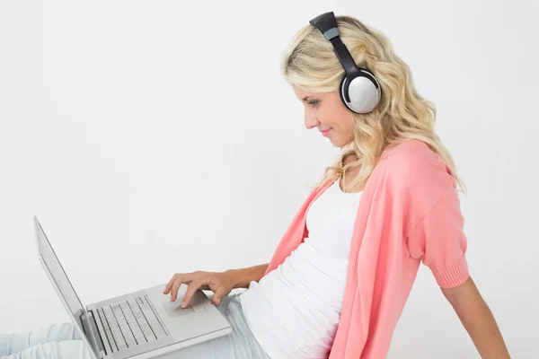 Mujer joven usando el ordenador portátil mientras escucha música —  Fotos de Stock