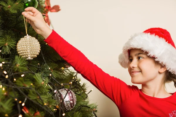 Festliches kleines Mädchen hängt eine Weihnachtsdekoration auf — Stockfoto