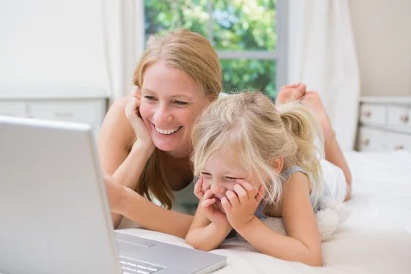 Menina e mãe na cama usando laptop — Fotografia de Stock