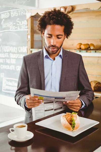 Бизнесмен за обедом читает газету — стоковое фото