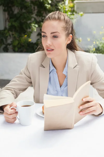 Beautiful businesswoman having a coffee reading book — Stock Photo, Image