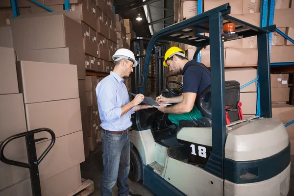 Magazijnbeheerder praten met heftruck chauffeur — Stockfoto