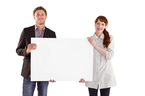 Smiling couple holding large sign — Stock fotografie