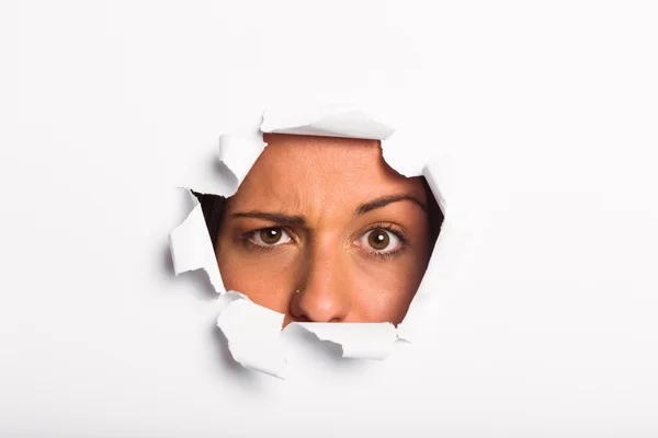 Young woman looking through paper rip — Stock Photo, Image