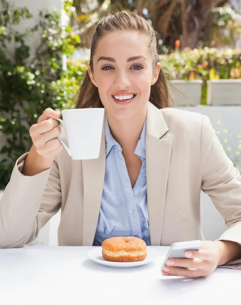 Красивая деловая женщина пьет кофе и кексы — стоковое фото