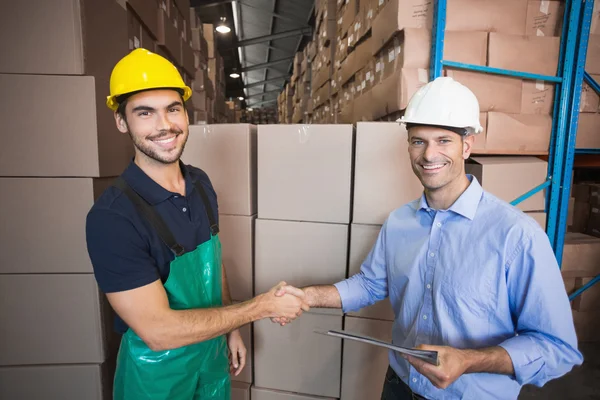 Warehouse worker loading up pallet with manager — Stock Photo, Image