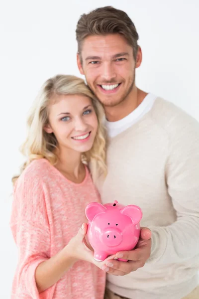 Attraktives junges Paar hält Sparschwein — Stockfoto