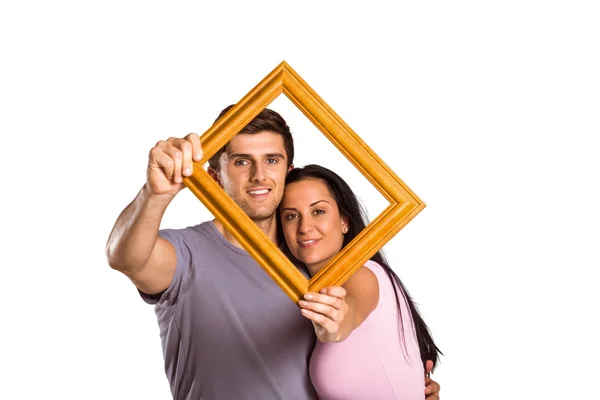 Jovem casal segurando quadro — Fotografia de Stock