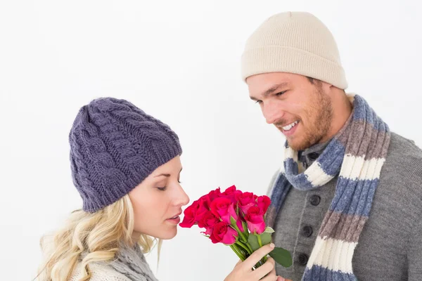 Casal atraente em roupas quentes segurando flores — Fotografia de Stock