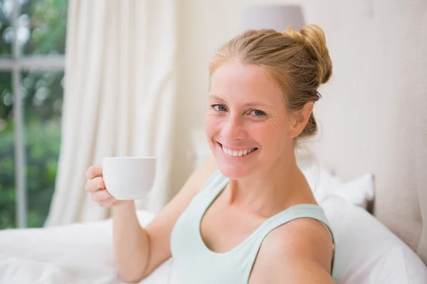 Glückliche Blondine trinkt Kaffee im Bett — Stockfoto