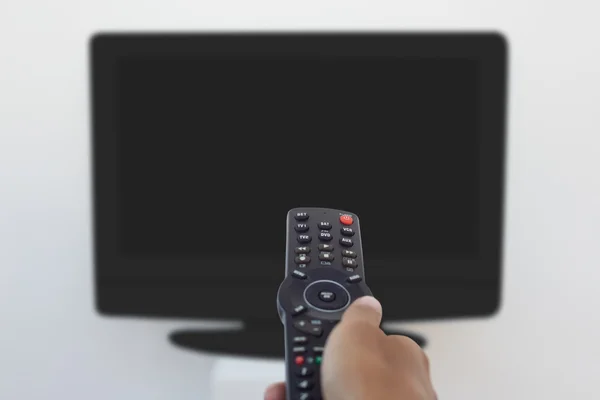 Hand holding remote and changing channel — Stock Photo, Image