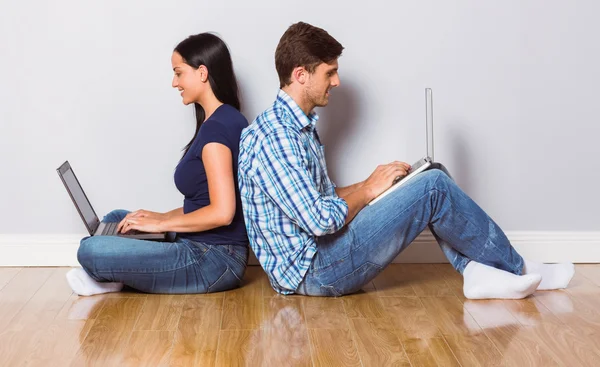 Jong koppel zittend op de vloer met behulp van laptop — Stockfoto