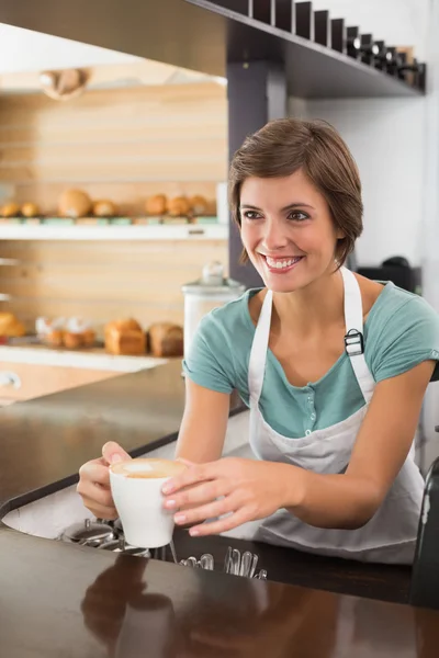 Hezká barista nabízí šálek kávy s úsměvem — Stock fotografie