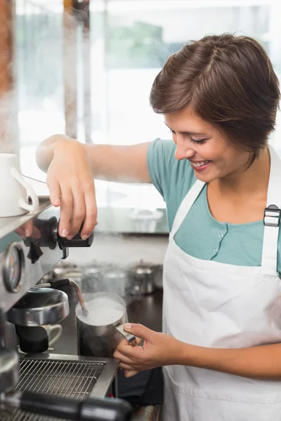 Pretty barista steaming jug of milk at coffee machine — Stock Photo, Image