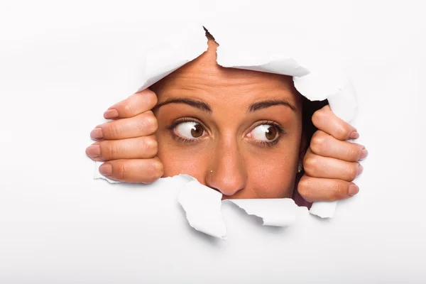 Young woman looking through paper rip — Stock Photo, Image